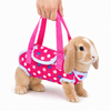 Pink rabbit carrier harness bag with polka dot design, bunny travel sling held by hand, white background product photo